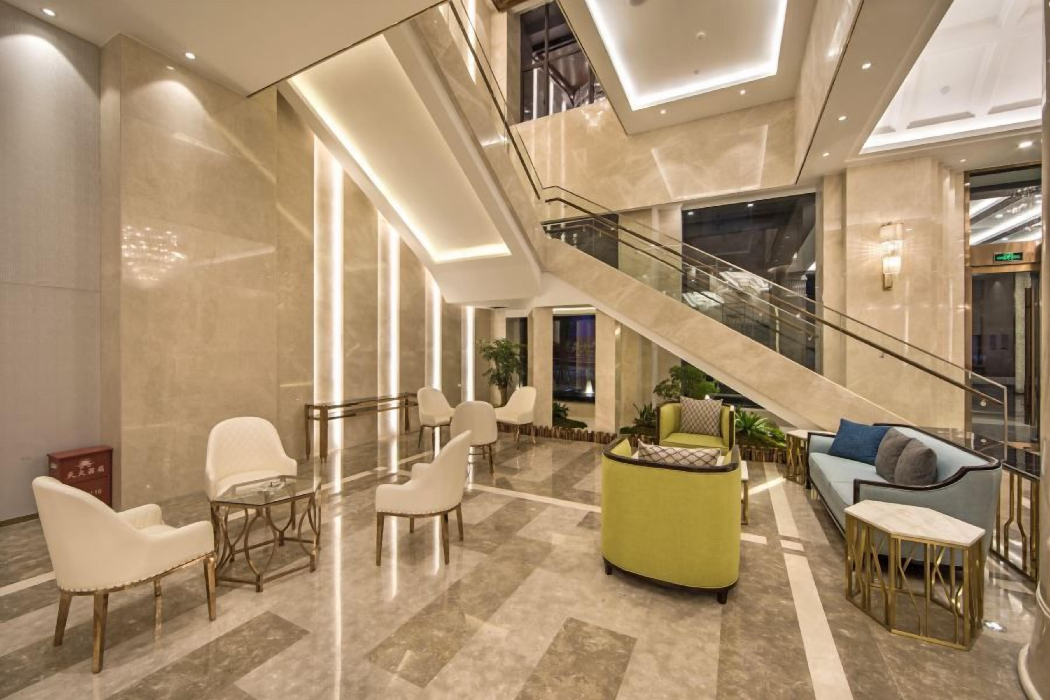 Un vestíbulo amplio con un área de descanso central, una escalera y un diseño moderno.