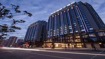 A high-rise hotel with multiple floors, large windows, and illuminated signage.