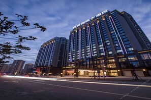 A high-rise hotel with multiple floors, large windows, and illuminated signage.