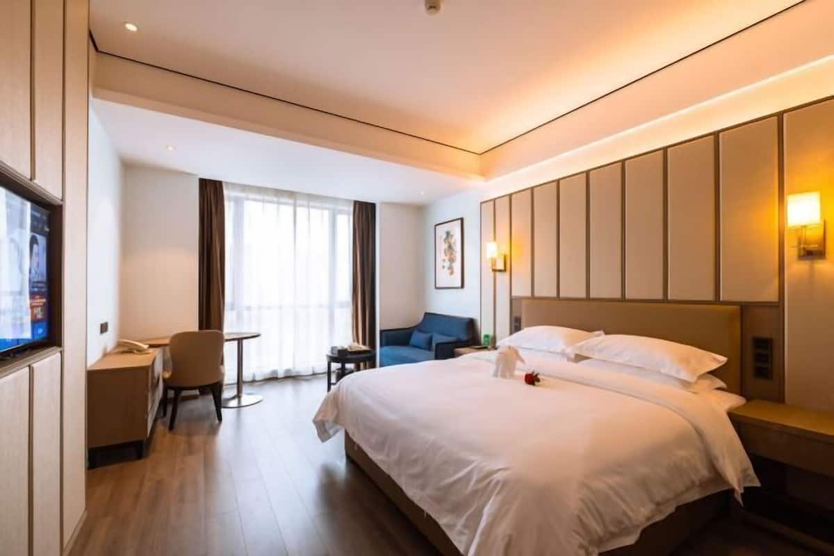 Une chambre d’hôtel avec un grand lit, un bureau, une chaise et un téléviseur.