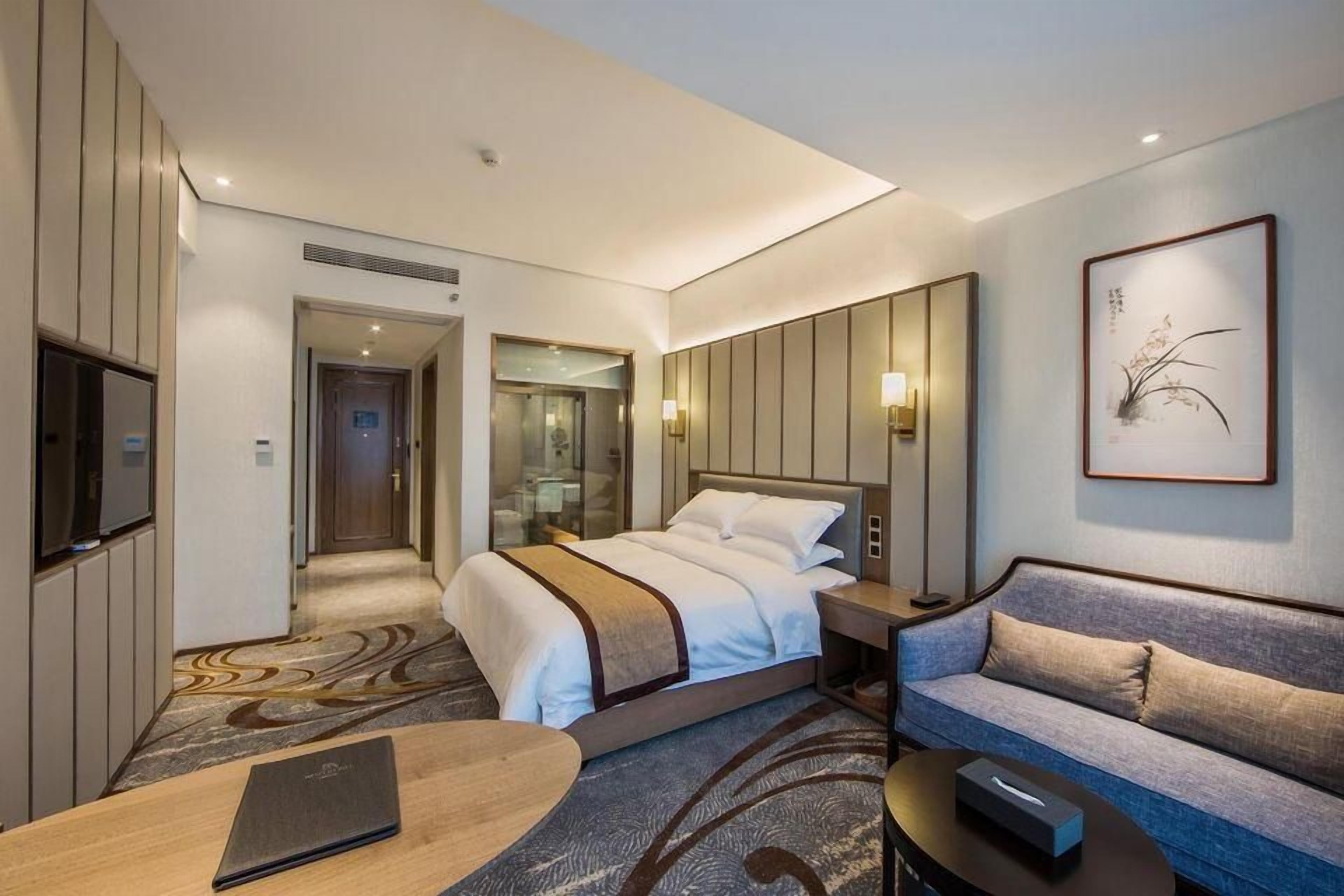 Habitación de hotel con cama, sofá, escritorio y televisor.