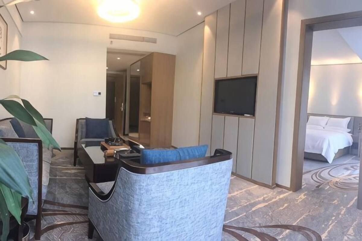 Une chambre d’hôtel avec un canapé, un bureau, une télévision et un lit.