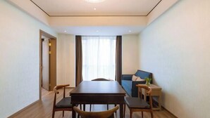 Une chambre d’hôtel moderne équipée d’une table à manger, de chaises, d’un canapé et d’une petite table d’appoint agrémentée d’une plante.