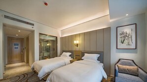 Une chambre d’hôtel avec deux lits, un coin salon et une œuvre d’art encadrée au mur.