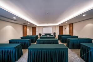 A conference room with multiple tables, a projection screen, and a carpeted floor. - West City International Hotel (Nanping)
