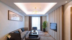 Une chambre d’hôtel moderne équipée d’un canapé, d’une table basse, d’une télévision et d’une grande fenêtre.