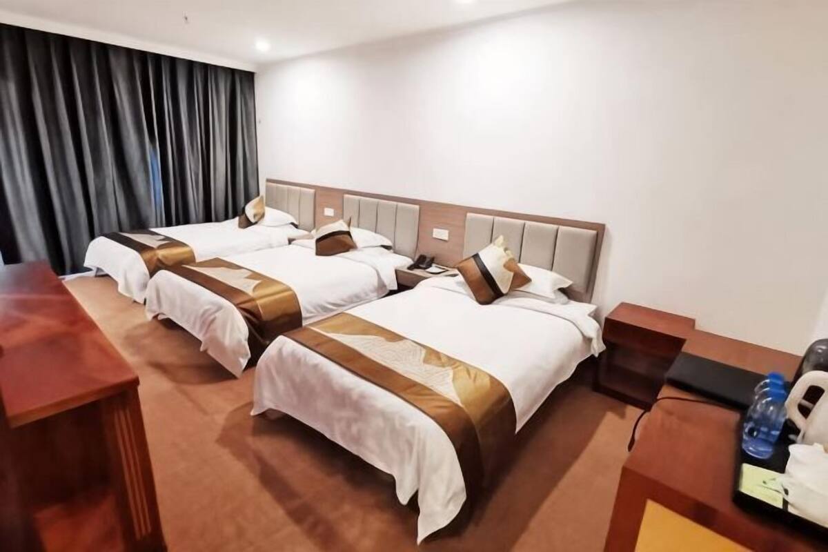 A hotel room with two beds, a desk, a chair, a telephone, and a water bottle.