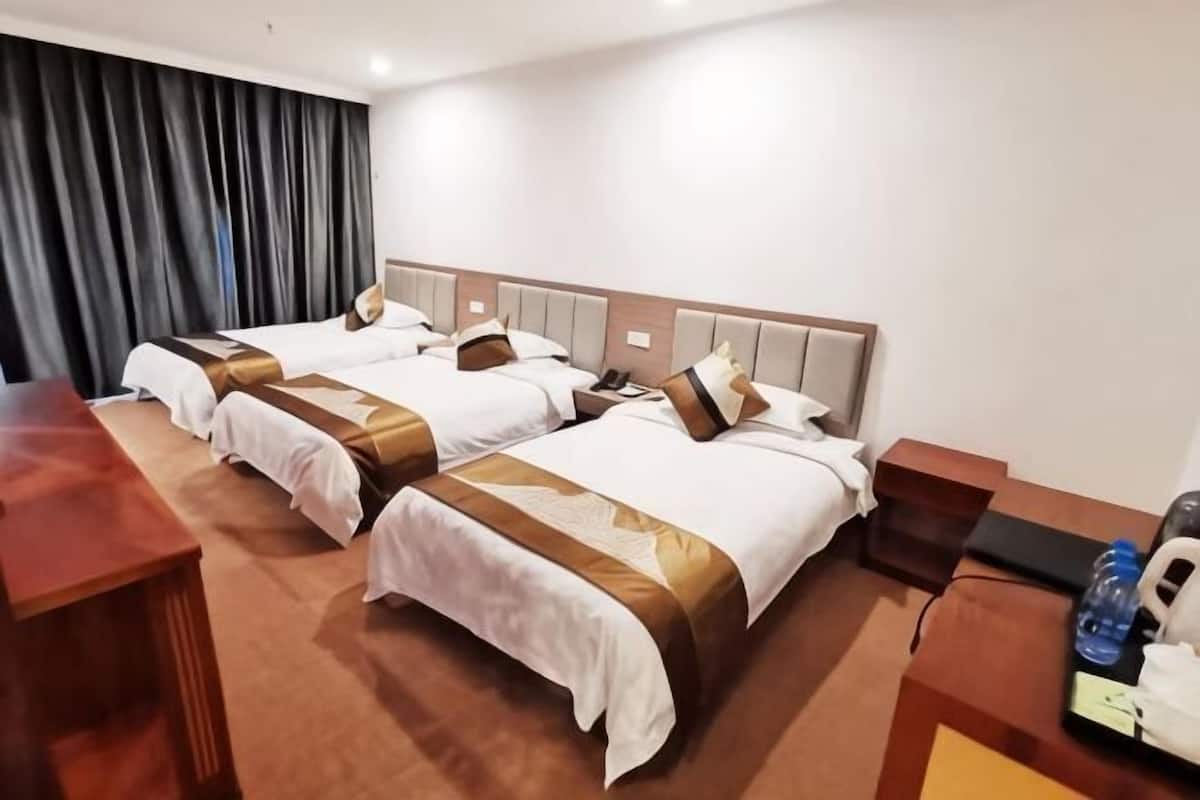A hotel room with two beds, a desk, a chair, a telephone, and a water bottle.