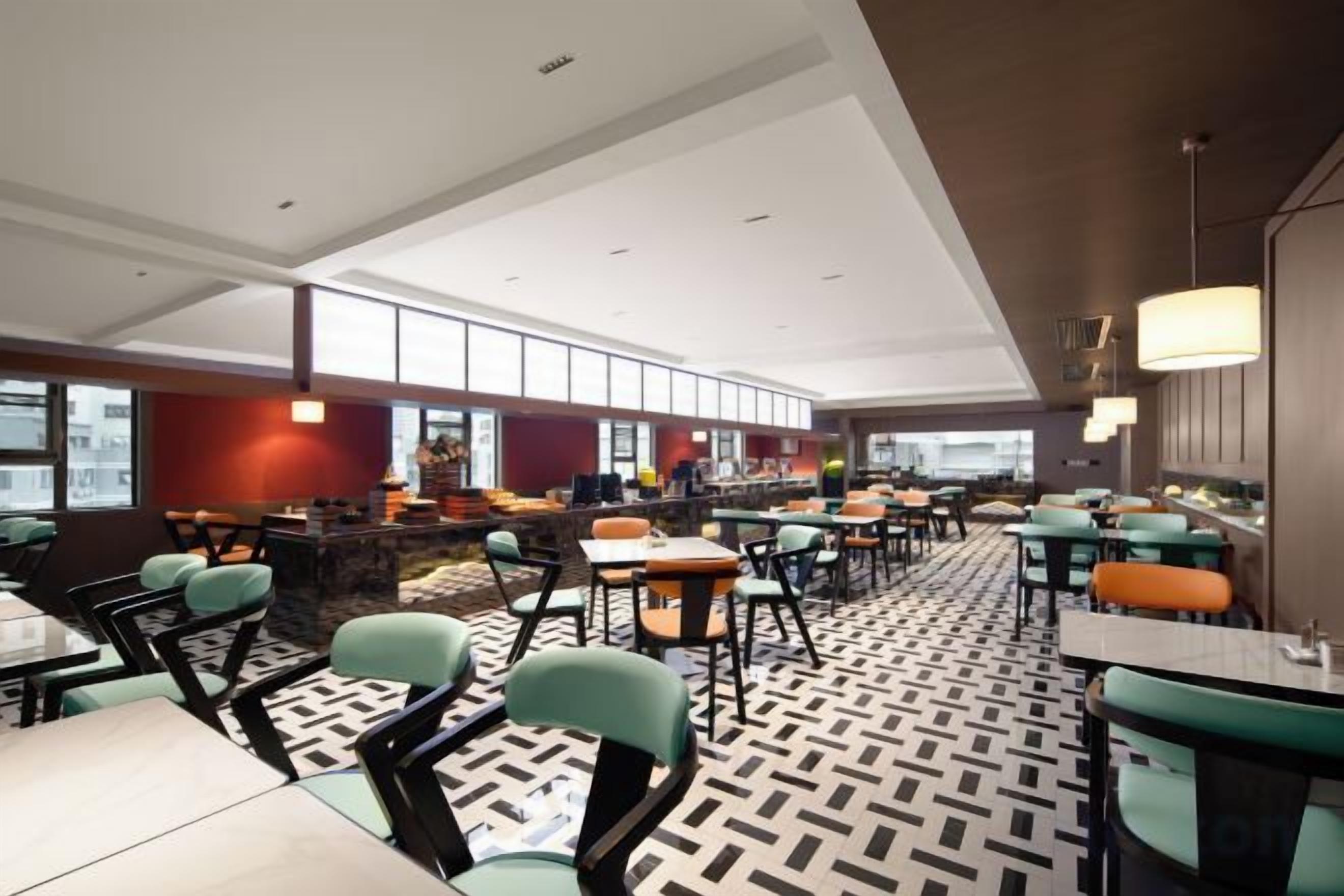 A modern restaurant with high ceilings, multiple dining areas, and a patterned floor.