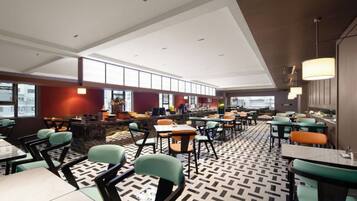 A modern restaurant with high ceilings, multiple dining areas, and a patterned floor.