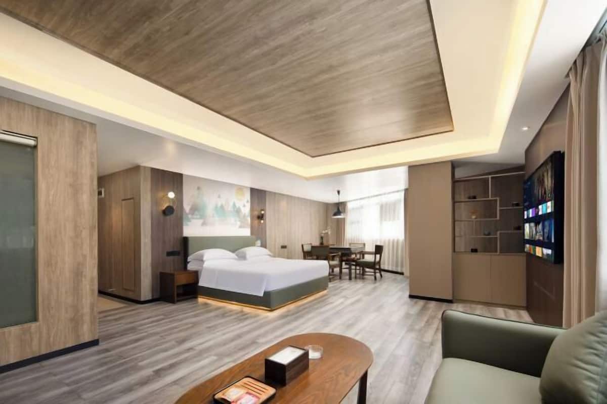 A modern hotel room with a large bed, a desk, and a seating area.