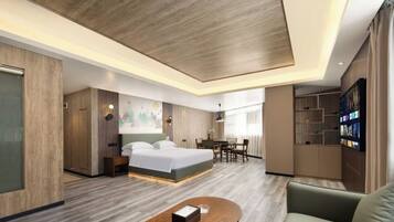 A modern hotel room with a large bed, a desk, and a seating area.