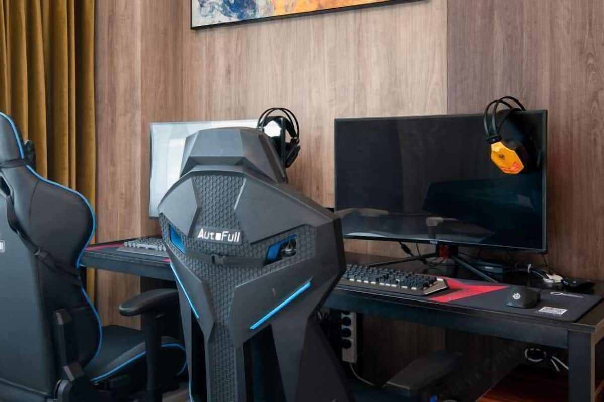 A gaming setup with two chairs, a desk, a monitor, and a keyboard.
