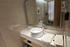 Un baño moderno con un espejo grande, un lavabo blanco y una zona de ducha.