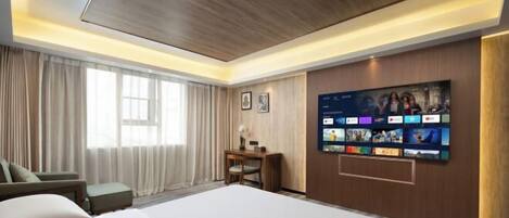 Habitación de hotel con una cama grande, un escritorio, una silla y un televisor de pared mostrando varios canales.