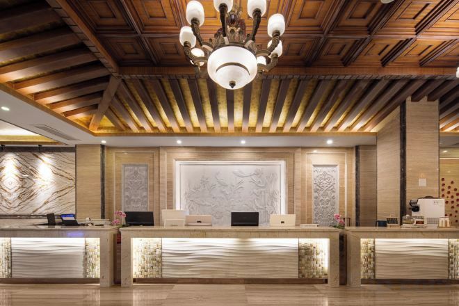 A reception area with a wooden ceiling, a chandelier, marble wall panels, and a reception desk.