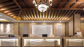 A reception area with a wooden ceiling, a chandelier, marble wall panels, and a reception desk.