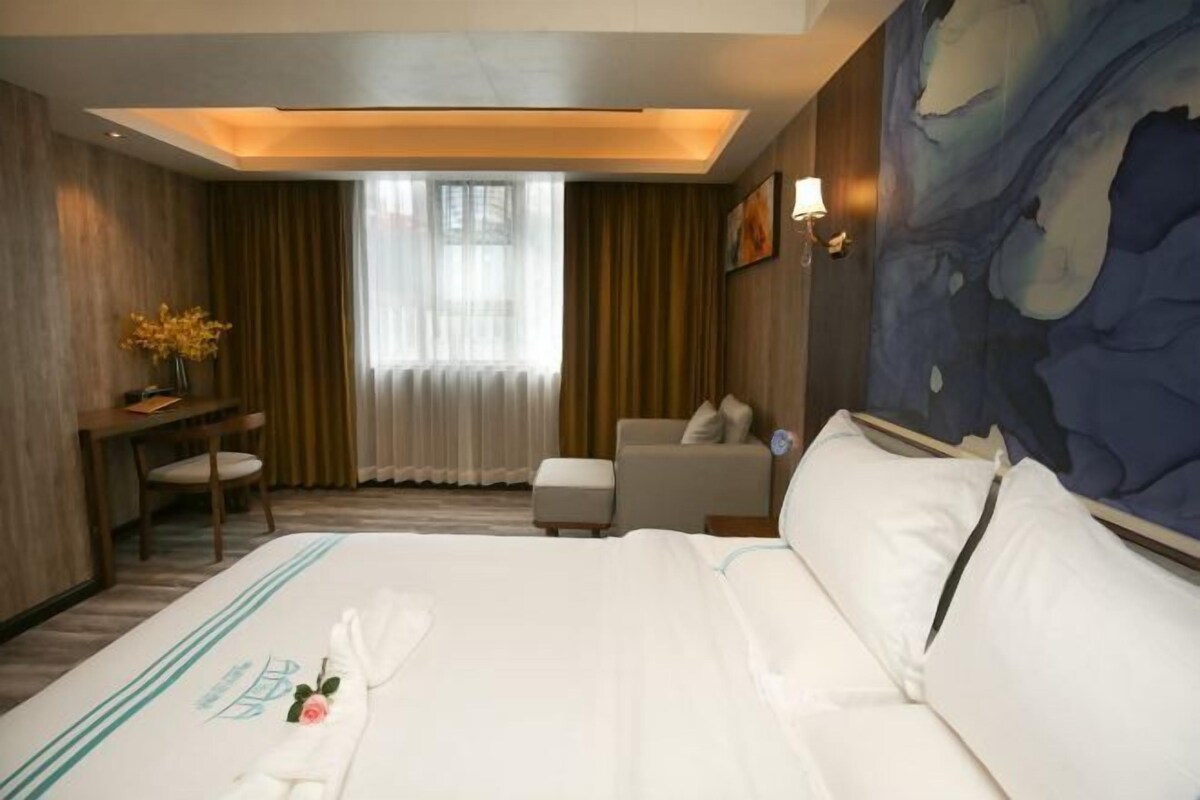 Habitación de hotel con una cama grande, un escritorio, una silla y un cuadro en la pared.