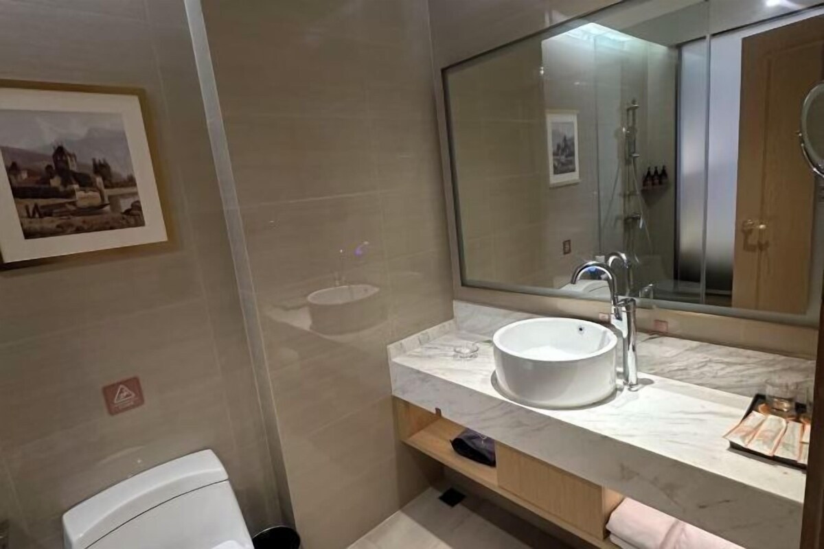 Un baño moderno con un espejo grande, un lavabo blanco y un inodoro.