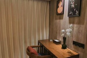 Una mesa de comedor de madera con un jarrón de flores blancas, un cojín rojo y una obra de arte enmarcada en la pared.
