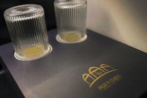Dos vasos de vidrio sobre una superficie oscura con un logotipo.