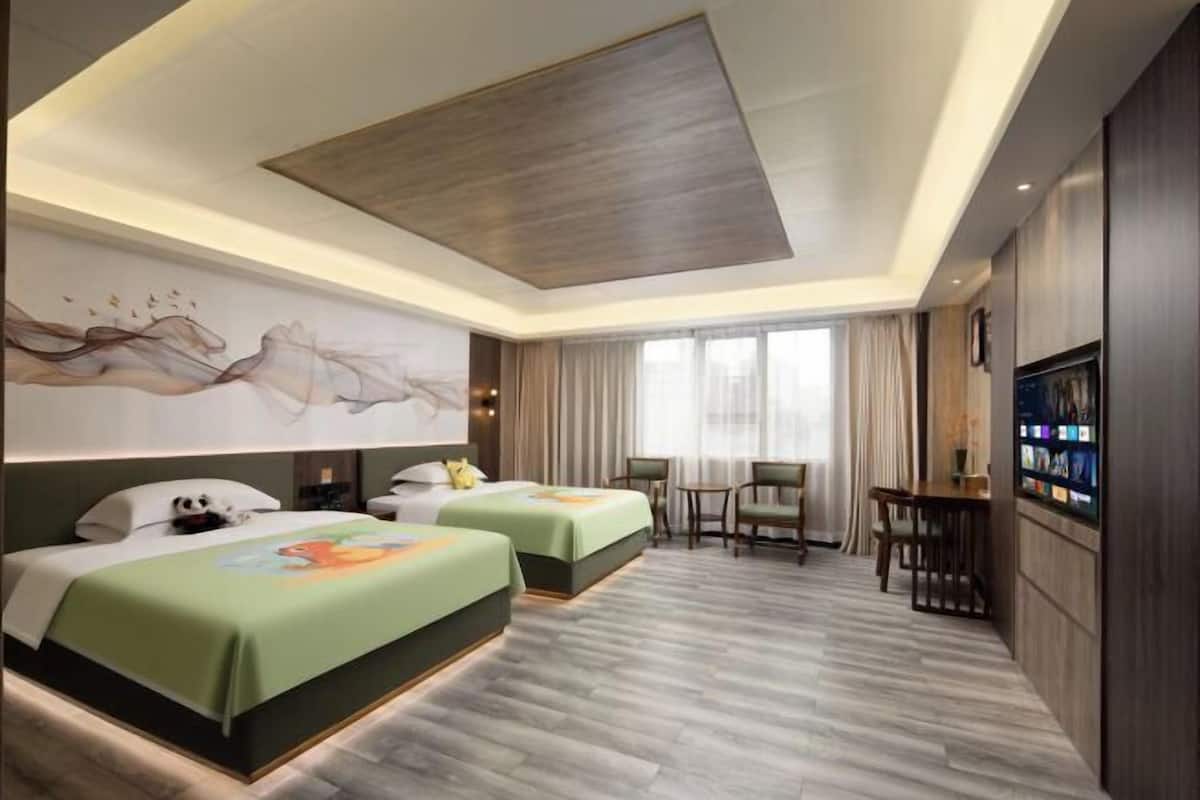 A hotel room with two beds, a desk, a chair, and a TV.