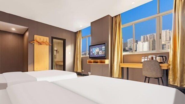 Camera d'albergo con un letto, una scrivania, un televisore e vista sulla città.