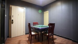 Una stanza con una porta in legno, un tavolo con sedie e uno specchio fissato al muro.