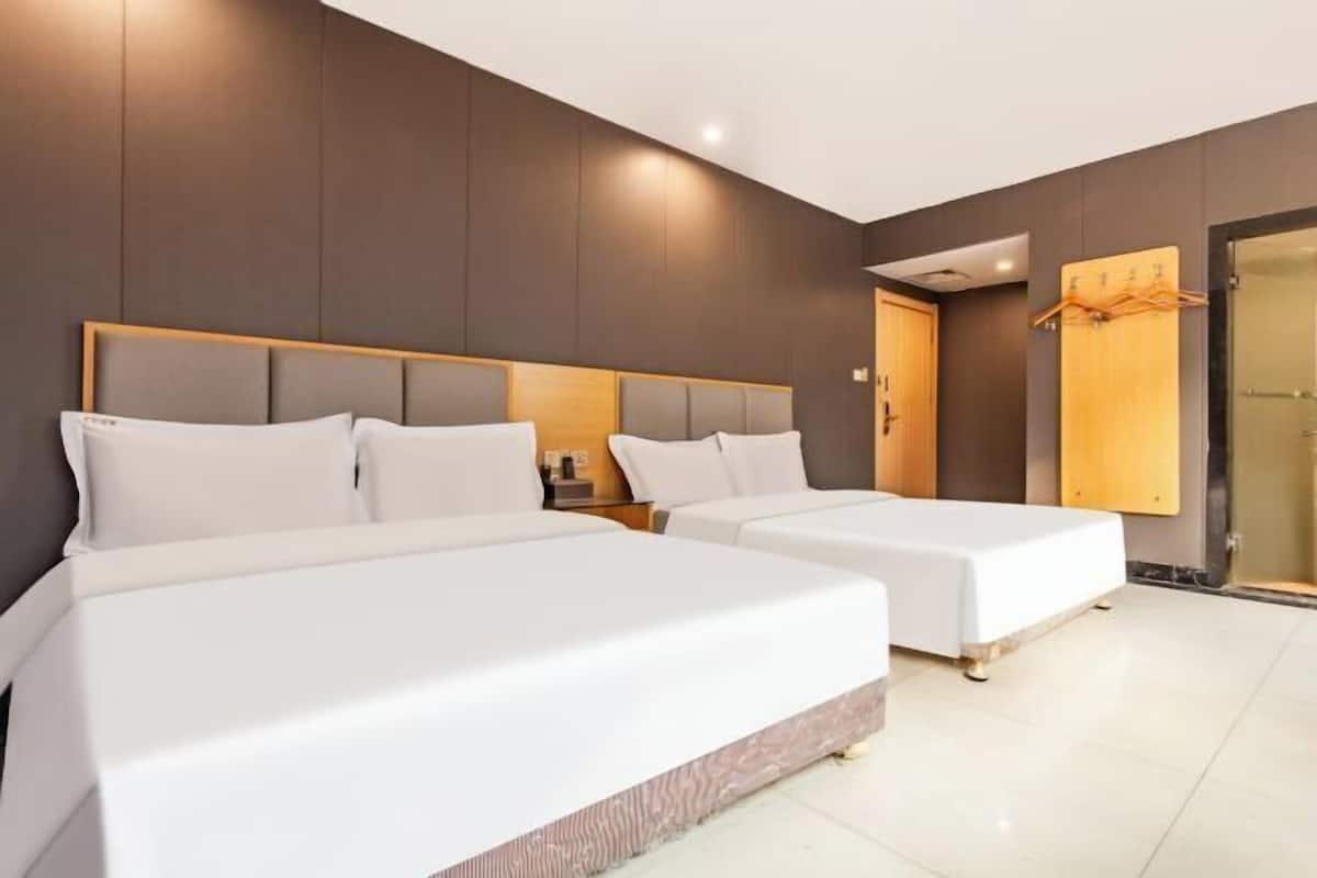 A hotel room with two beds, a wooden headboard, a wooden door, and a coat rack.