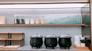 Uma cozinha com três bocas elétricas, uma prateleira com potes e uma pintura emoldurada de uma paisagem.