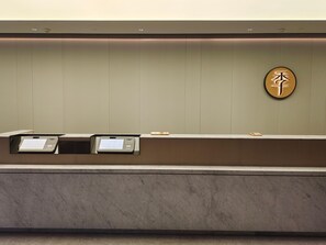 Ein Empfangsschalter mit einem digitalen Kiosk, einem Wandzeichen in chinesischen Schriftzeichen und einer Marmorarbeitsplatte.