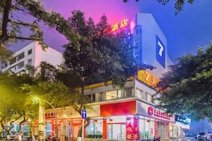 Ein Hotel mit einer auffälligen Schautafel, einem großen, blauen Pfeilschild und einer Neonreklame über dem Eingang.