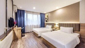 Une chambre d’hôtel avec deux lits, un bureau, une télévision et une fenêtre avec des rideaux.