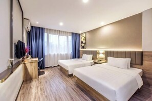 A hotel room with two beds, a desk, a TV, and a window with curtains.