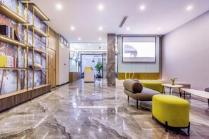 A hotel lobby with a marble floor, seating area with yellow chairs, a reception desk, and a bookshelf. - 7 Days Inn (Rongchang Commercial Pedestrian Street) (Chongqing)