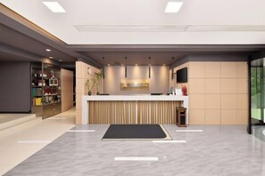 A modern reception area with a reception desk, a plant, and a counter with a television. - Jinjiang Inn Style (Huaxi District Xiahe Vanke Metropolis Store GuiyangGuizhou) (Guiyang)
