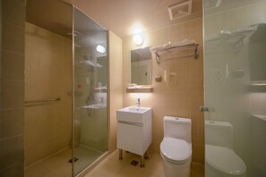 Un baño con ducha envuelta en cristal, un lavabo blanco y un inodoro.