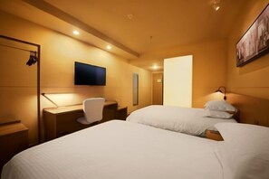 Habitación de hotel con dos camas, un escritorio, una silla, un televisor de pantalla plana y un cuadro colgado en la pared.