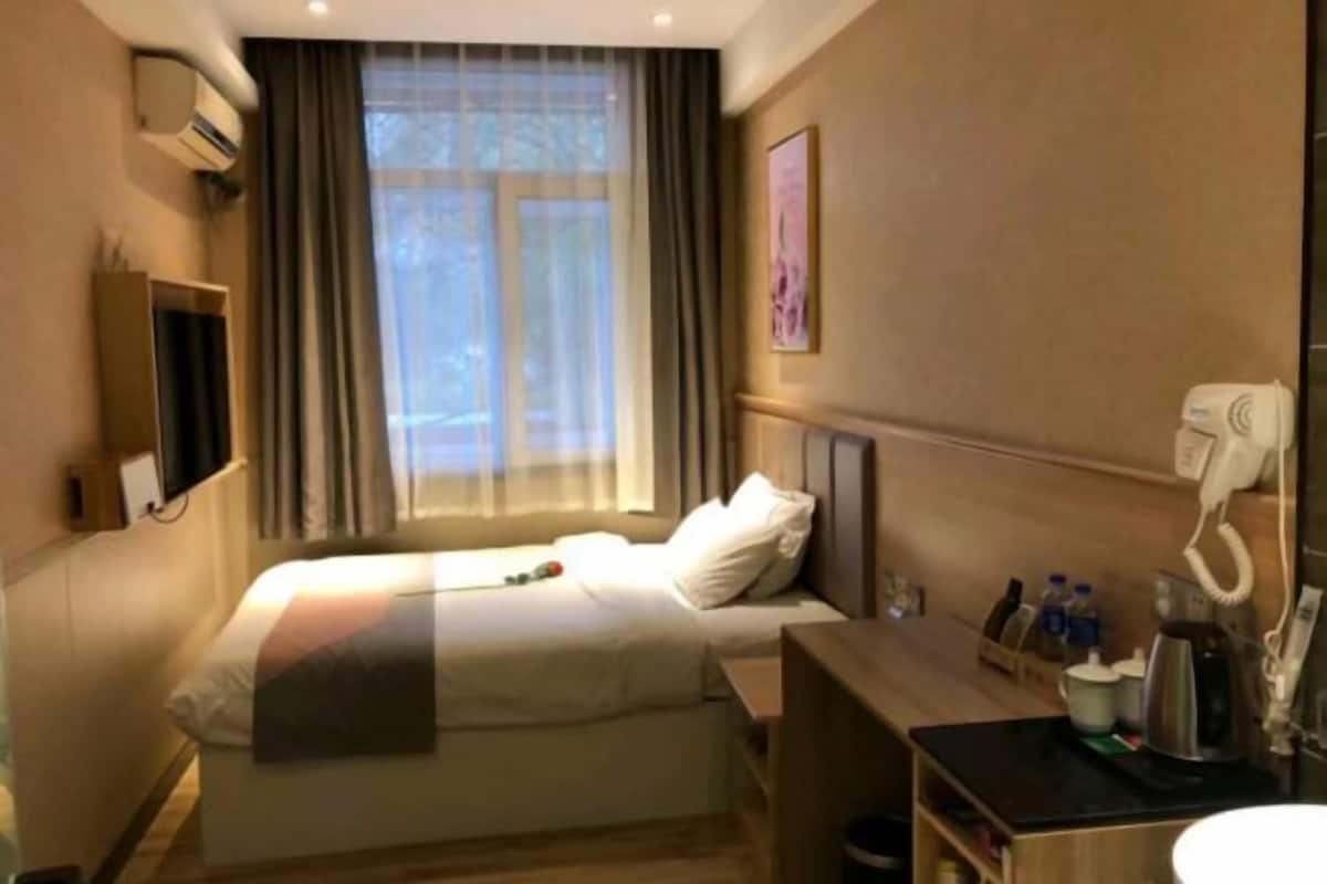 Quarto de hotel com cama, escrivaninha, cadeira, cafeteira e telefone.
