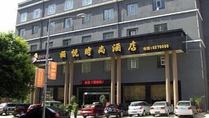 Een hotel met meerdere verdiepingen, een donkere gevel en een bord met gele letters.