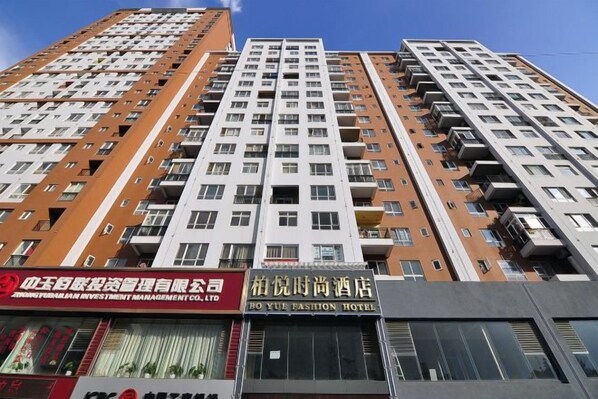 A high-rise building with multiple floors, balconies, and a commercial ground floor with signage.