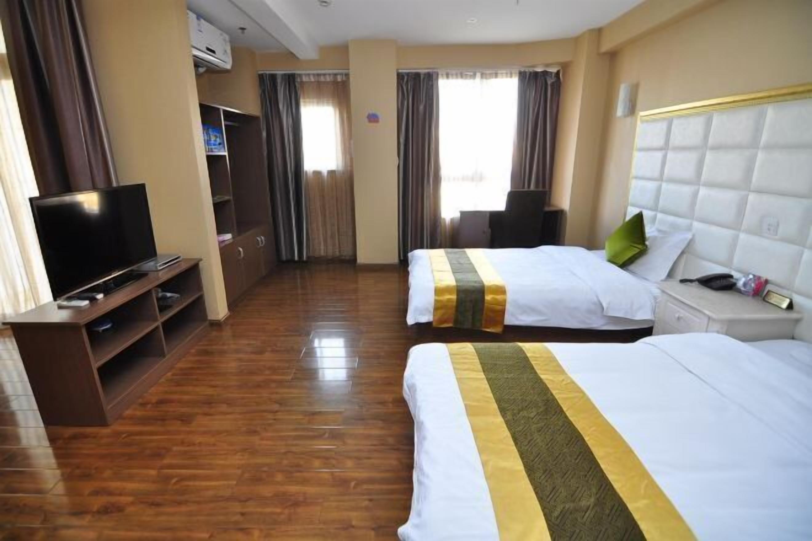 A hotel room with two beds, a TV, a desk, and a wardrobe.
