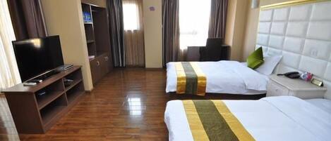 A hotel room with two beds, a TV, a desk, and a wardrobe.