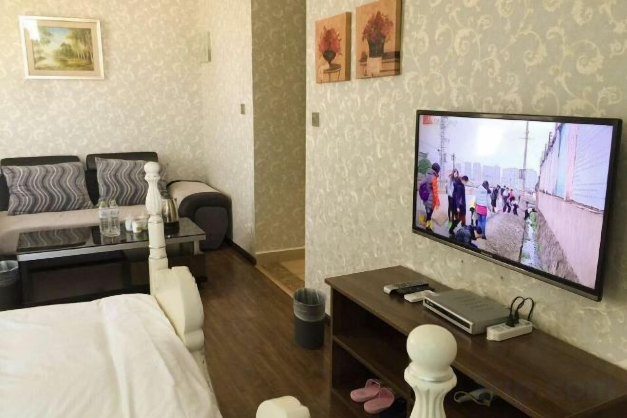 A hotel room with a bed, a sofa, a TV, and a desk.