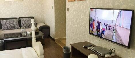 A hotel room with a bed, a sofa, a TV, and a desk.