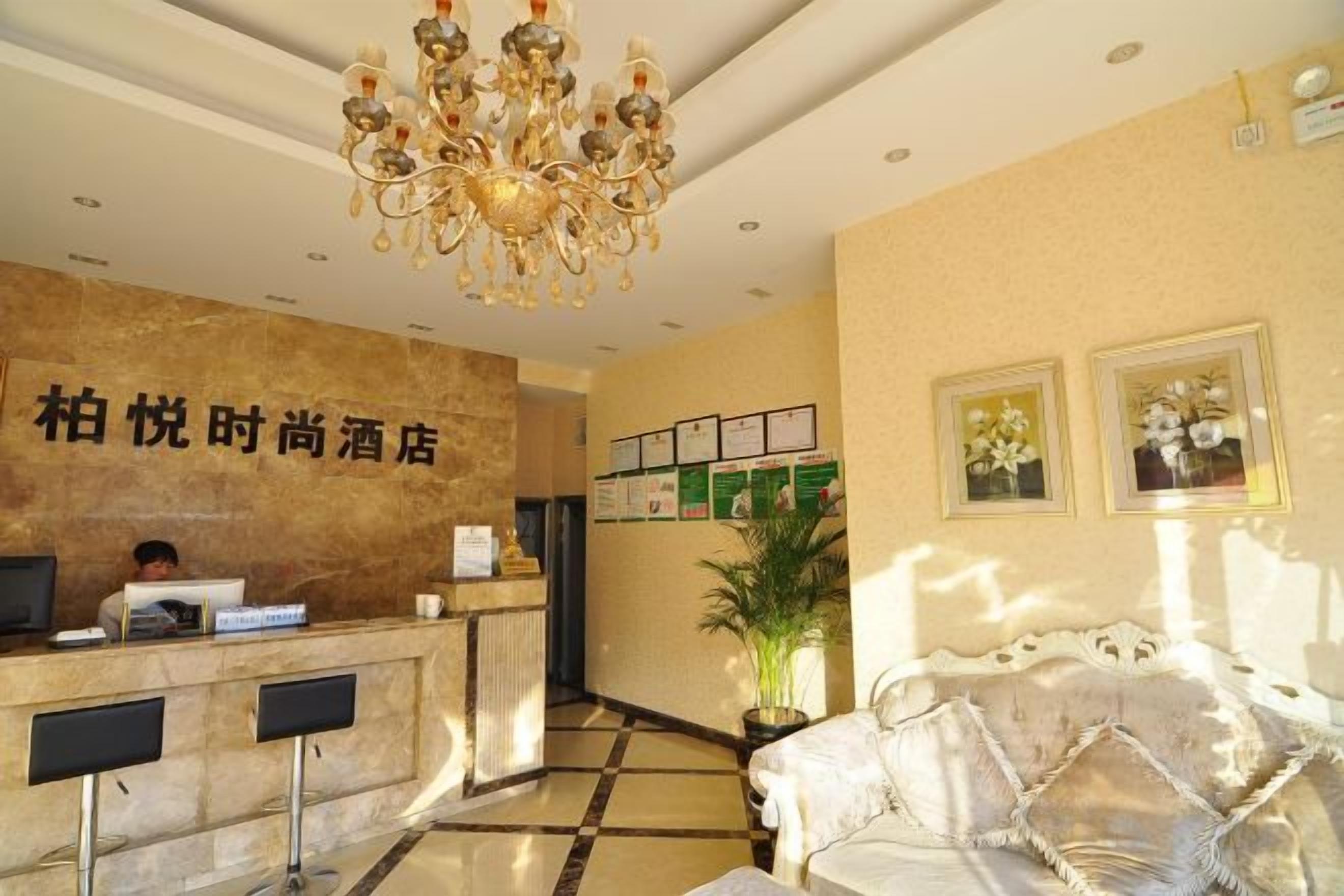 A hotel reception area with a marble counter, a chandelier, and a sofa with a patterned cover.