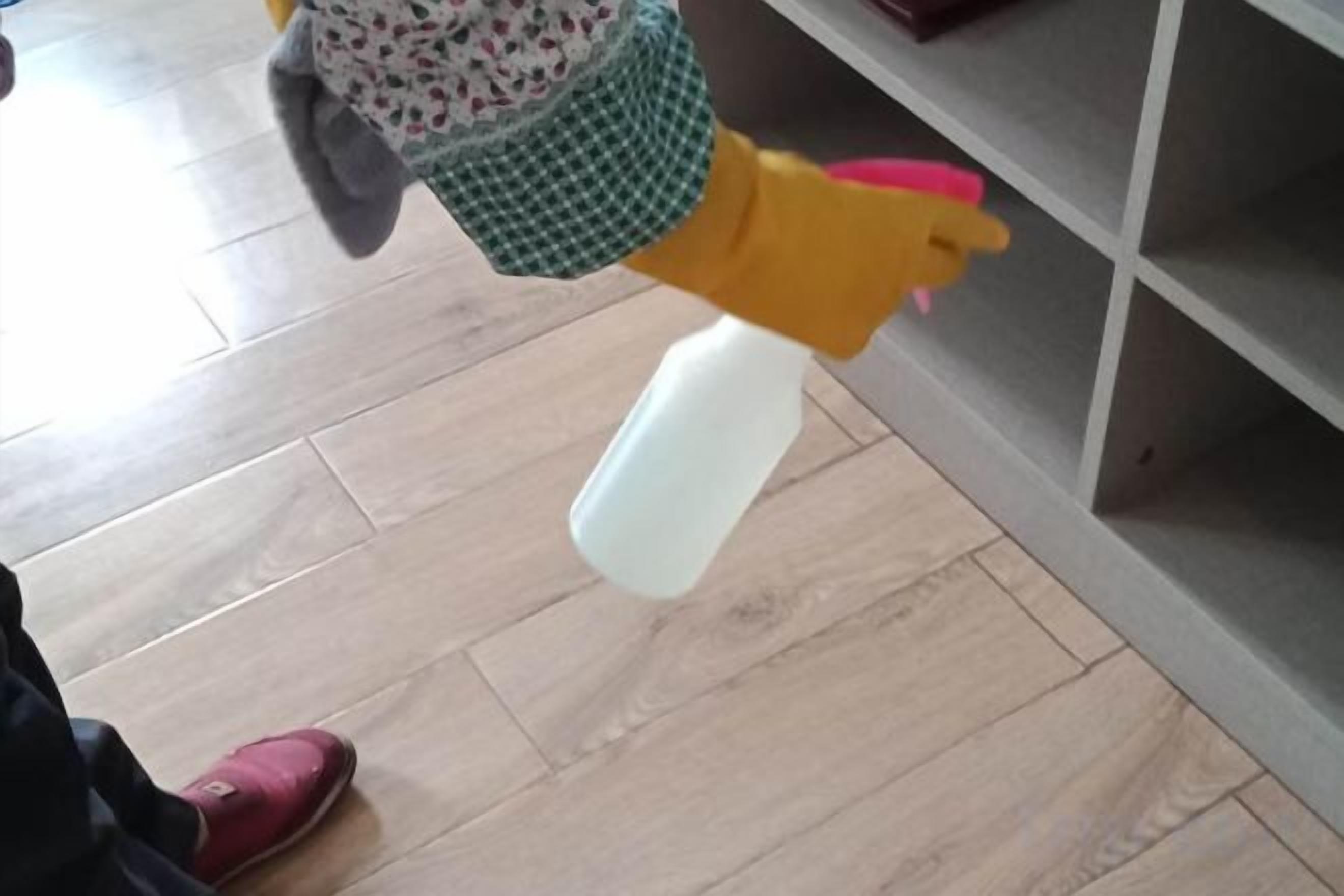 A person holding a spray bottle, likely cleaning or disinfecting a surface.