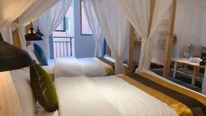 Hotelkamer met twee bedden, witte lakens, een hemelbed, een kleine tafel en uitzicht op het omliggende landschap.