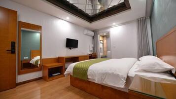 A hotel room with a bed, a TV, a mirror, and a skylight.