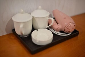 A black tray with three white ceramic cups and a pink electric kettle on a wooden table. - Tiancheng Jiudian (Zhongjiang)